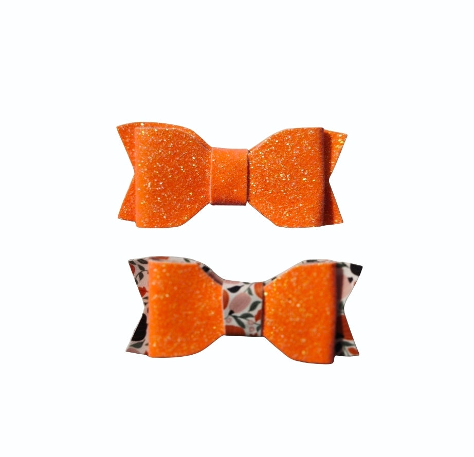 Handmade bright orange glitter faux leather Halloween hair bow set with pumpkin print for babies, toddlers, and girls.