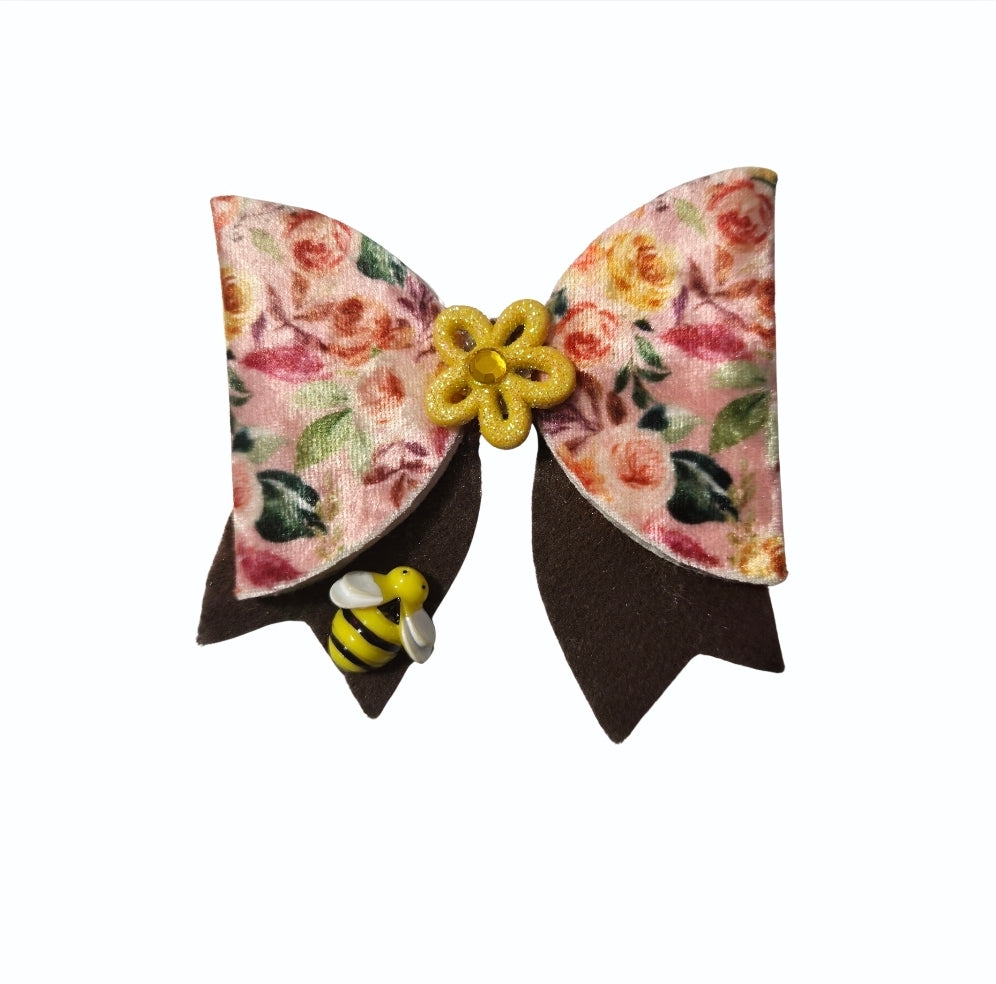 Handmade fall floral hair bow featuring pink and peach flowers, chocolate-brown tails, a yellow flower centerpiece, and a small bumblebee charm.