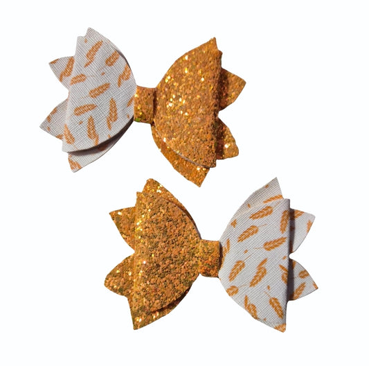 Handmade 2-pack medium faux leather hair bow set featuring gold glitter and autumn leaf print for babies, toddlers, and girls.