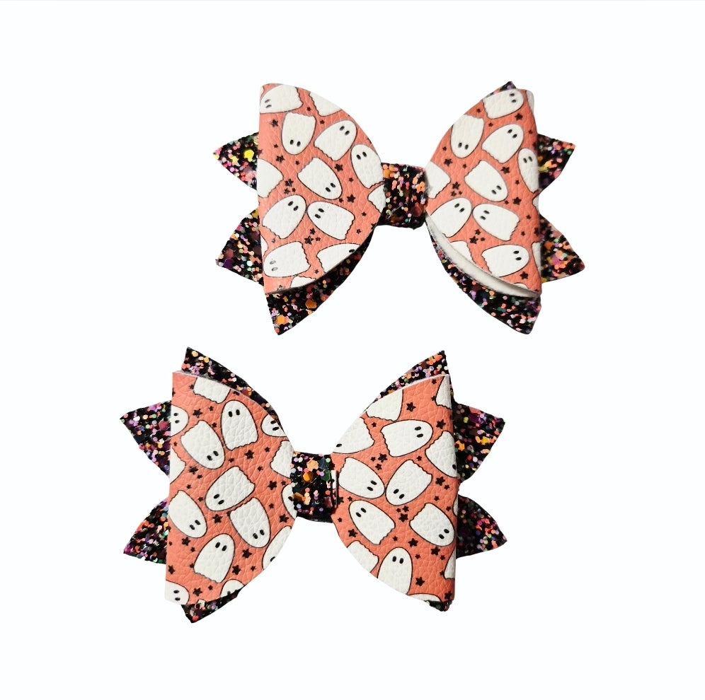 Two handmade Halloween ghost print medium hair bows with black glitter accents for babies, toddlers, and little girls.