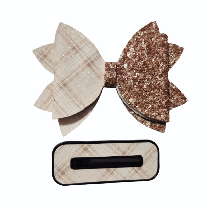 Close-up of a layered hair bow with soft cream plaid on one side and chunky gold glitter on the other.