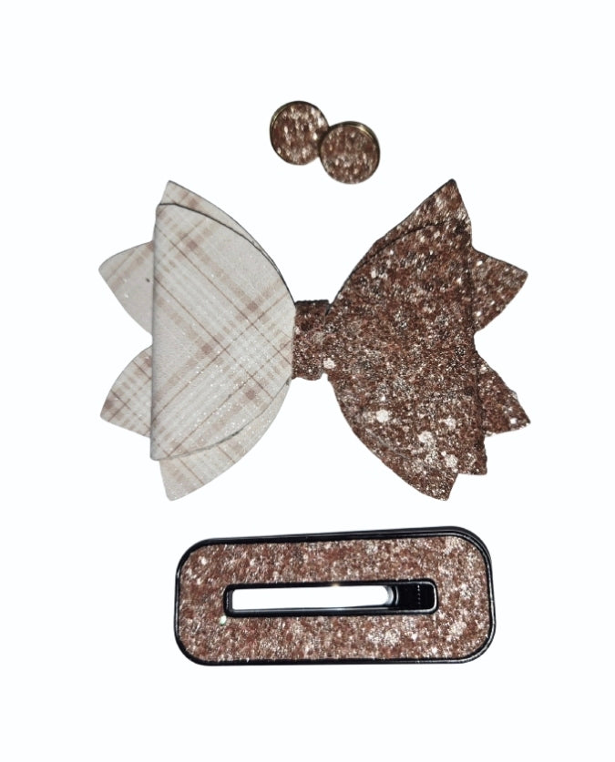 Close-up of a layered hair bow with soft cream plaid on one side and chunky gold glitter on the other.
