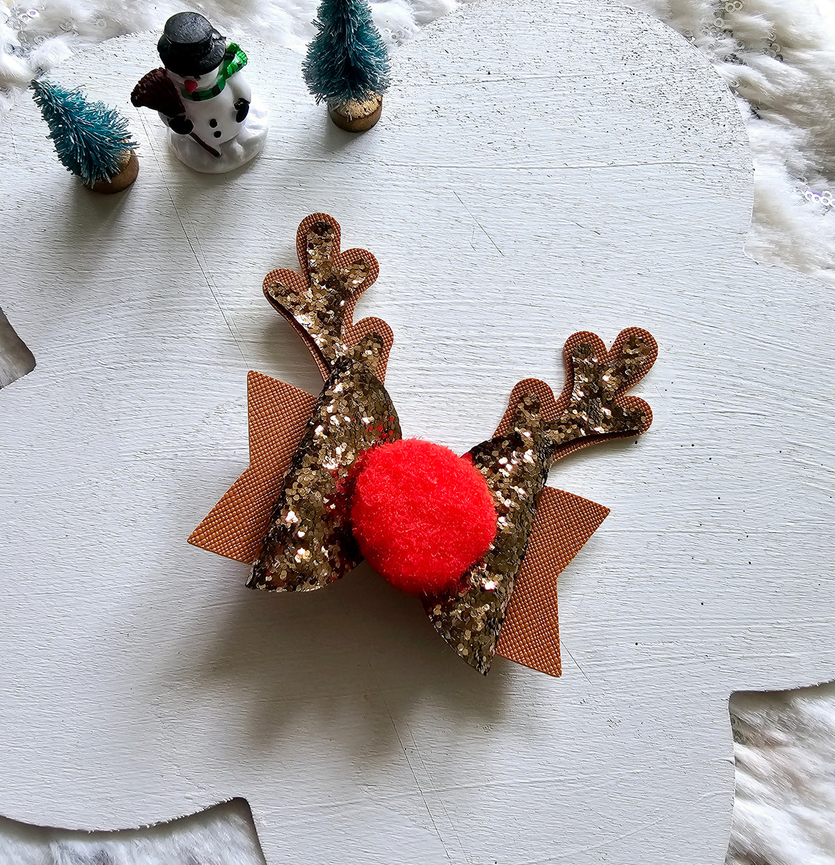 Handmade brown reindeer Christmas hair bow with glitter antlers, closed eyelashes, fluffy black nose and sparkling brown ribbon layers.
