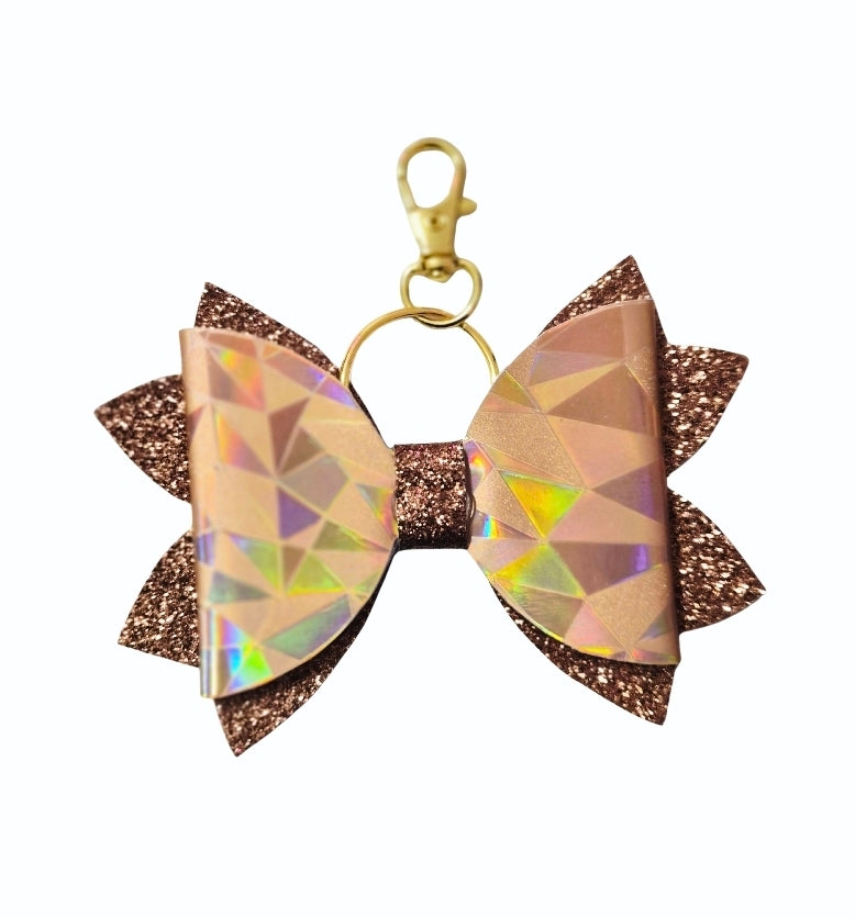 Handmade bow keychain featuring caramel holographic geometric faux leather, chocolate-brown glitter layers and a gold-tone lobster clasp.