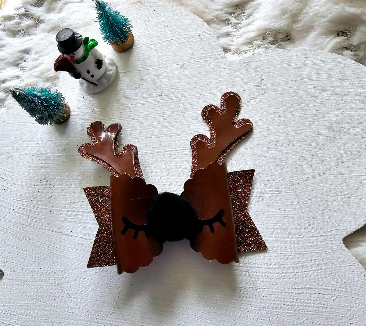 Handmade brown reindeer Christmas hair bow with glitter antlers, closed eyelashes, fluffy black nose and sparkling brown ribbon layers.