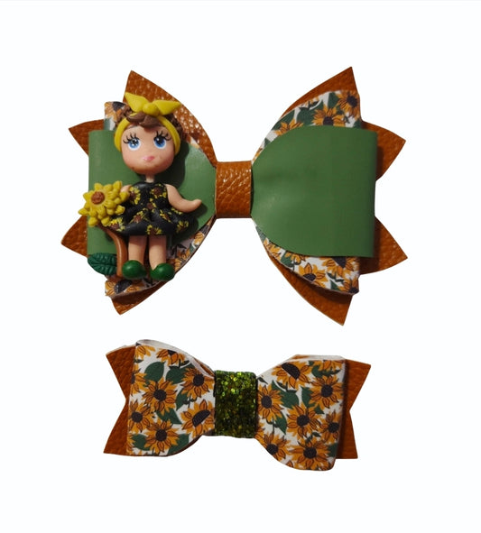 Matching sunflower hair bow set featuring a medium olive green and burnt orange bow with a sunflower girl centerpiece and a coordinating mini floral bow.