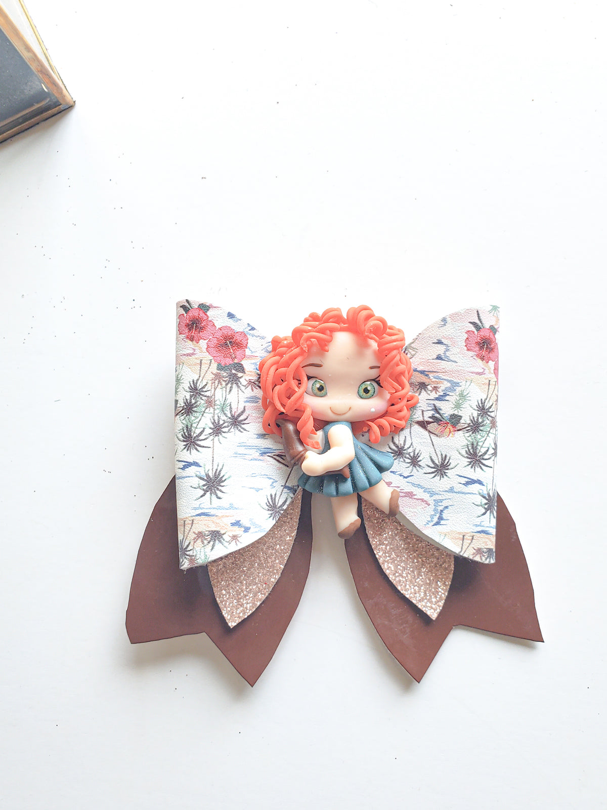 Chocolate Tropical Paradise girls' hair bow featuring layered brown tails, floral faux leather, glitter accents, and a decorative character.