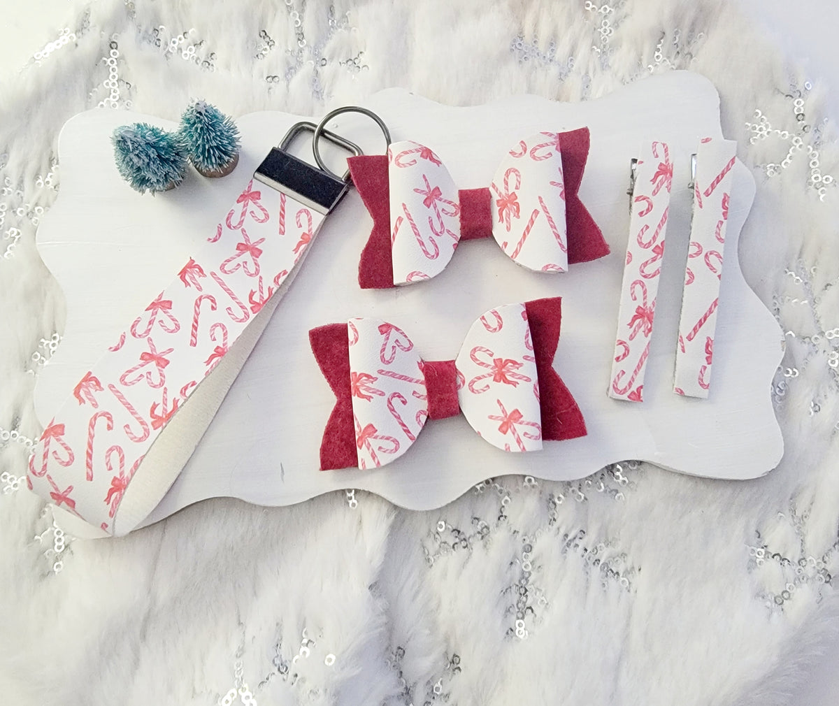 Two matching Christmas hair bows featuring white candy cane print fabric, red accents and festive holiday embellishments.