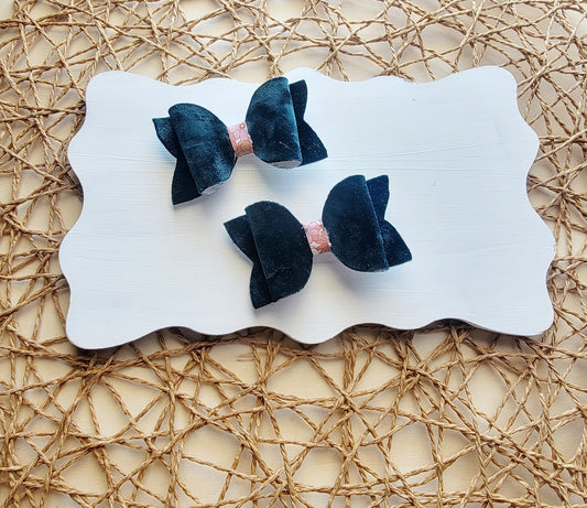 Pink floral faux leather hair bows with navy blue backing displayed together on a white board.