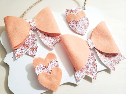 Matching peach fall hair bows and floral pumpkin-patterned clips arranged together as a handmade girls' accessory set.
