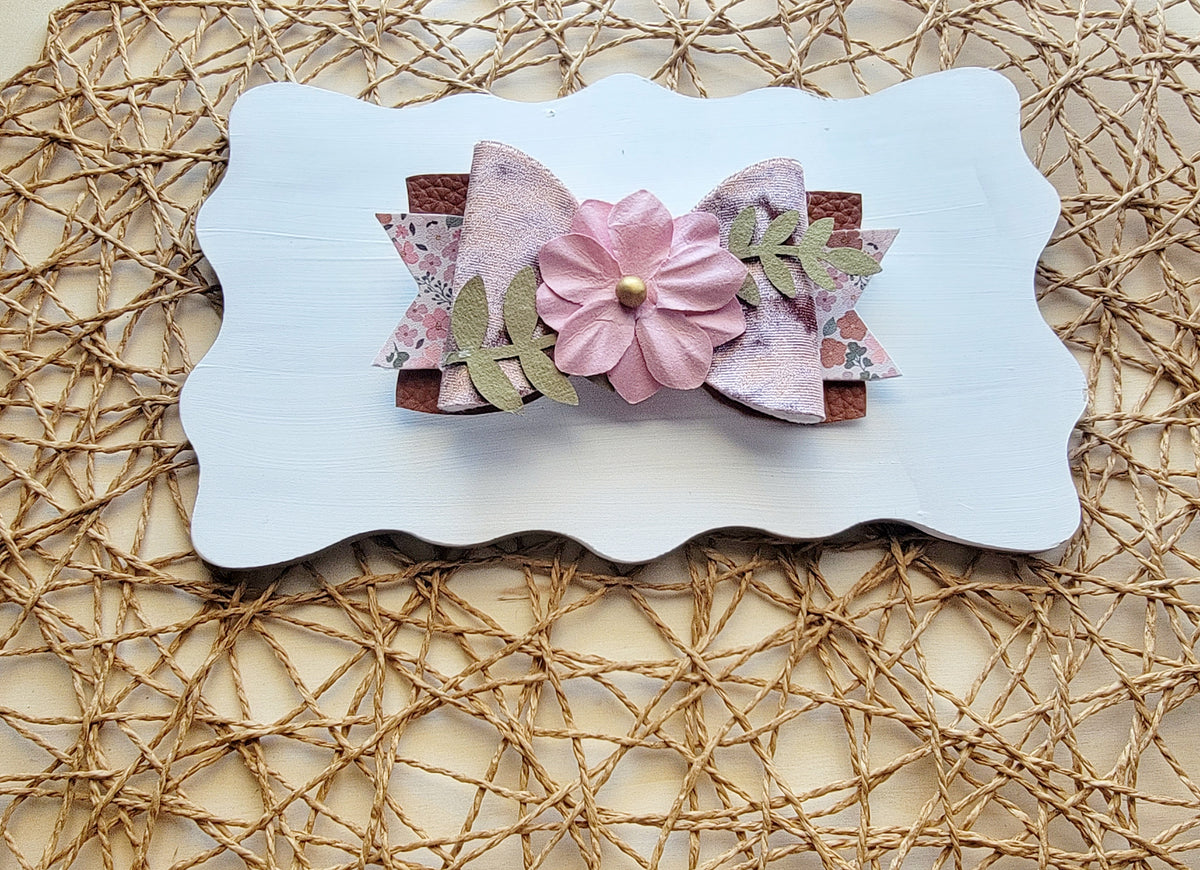 Layered pink floral hair bow with a decorative pale pink flower centerpiece and glitter accents.